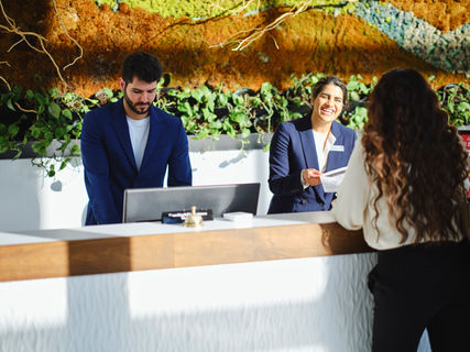 Hotel reception staff smiling and greeting a guest